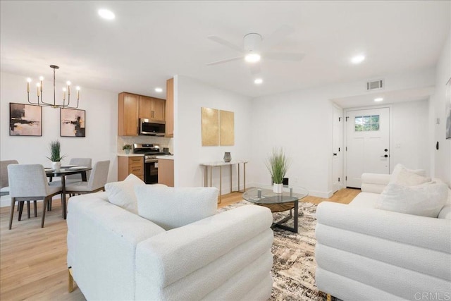 living room featuring recessed lighting, visible vents, light wood-style flooring, and ceiling fan with notable chandelier