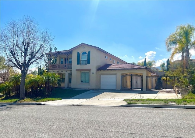 mediterranean / spanish home featuring driveway, an attached garage, a gate, fence, and stucco siding