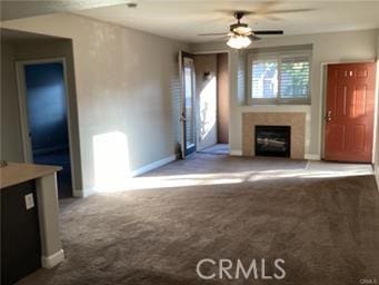 unfurnished living room with a ceiling fan, carpet flooring, a fireplace, and baseboards