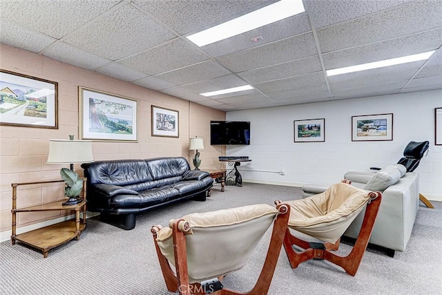 carpeted living area featuring concrete block wall