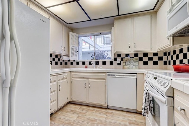 kitchen with white appliances, wood finish floors, tasteful backsplash, and a sink