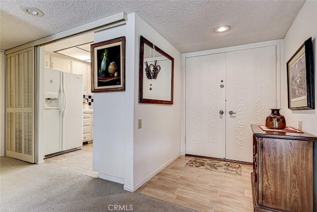 entryway with wood finish floors, baseboards, and a textured ceiling