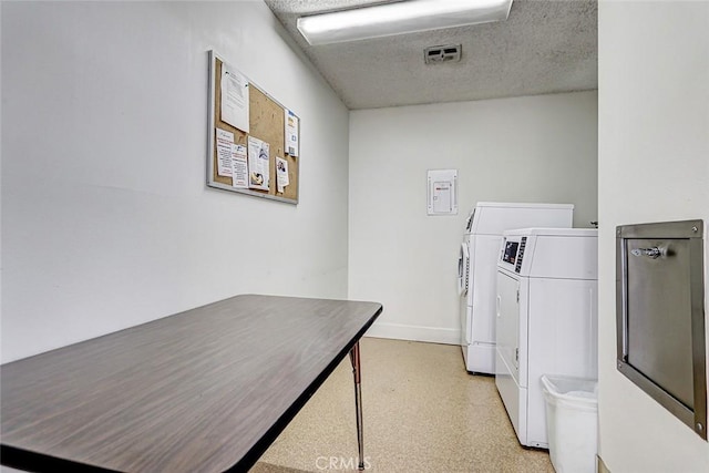 shared laundry area featuring baseboards, a textured ceiling, and washing machine and dryer