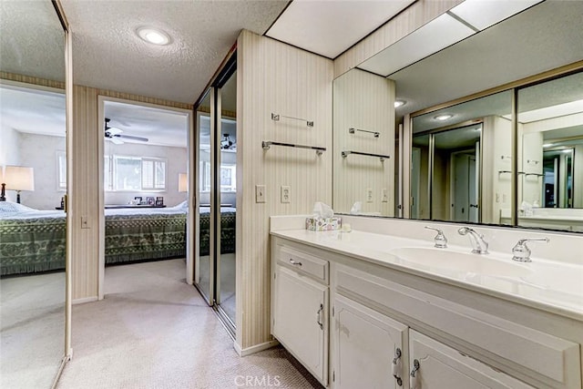 bathroom featuring vanity, a textured ceiling, ensuite bath, and a ceiling fan