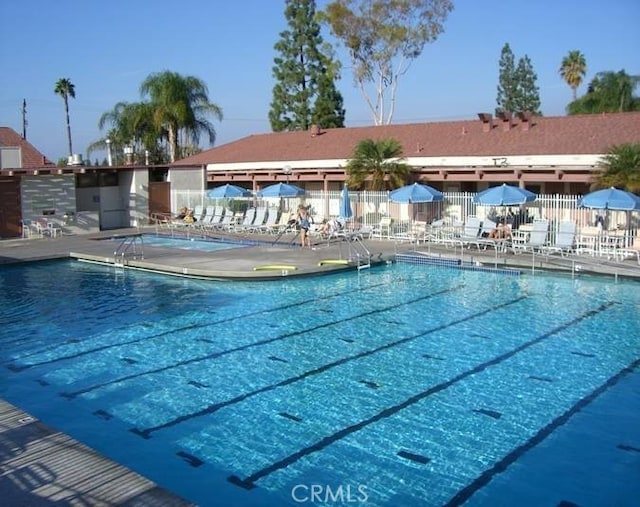 community pool with a patio area and fence