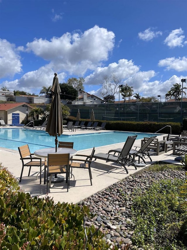 community pool with a patio area and fence