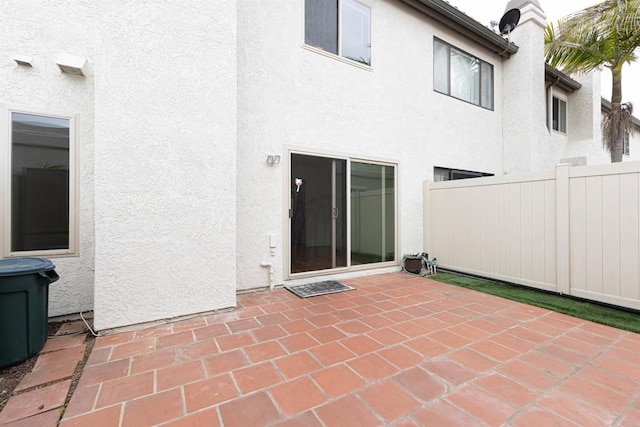 back of property with stucco siding, a patio, and fence