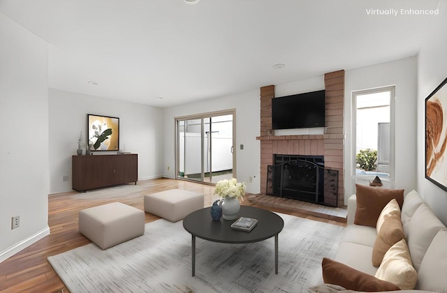 living area featuring a brick fireplace, wood finished floors, and baseboards