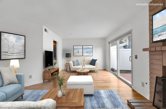 living area featuring a fireplace, wood finished floors, visible vents, and baseboards