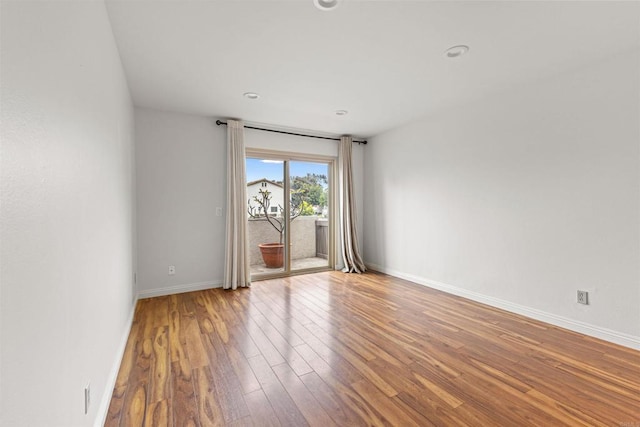 spare room featuring recessed lighting, wood finished floors, and baseboards