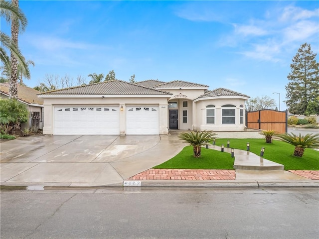 view of front of property with driveway, a tile roof, an attached garage, a front lawn, and stucco siding