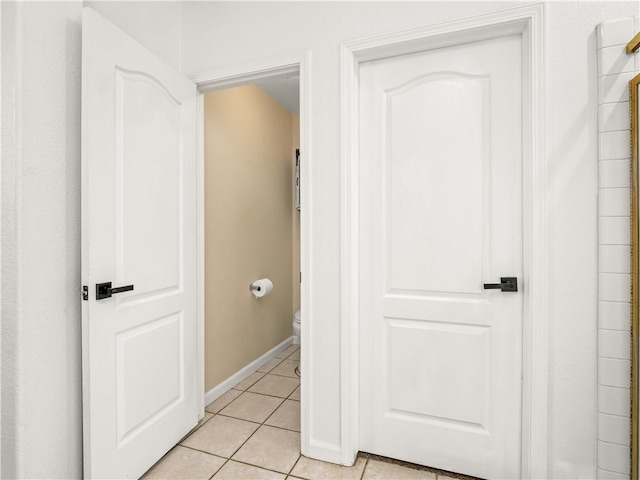 hall with light tile patterned flooring and baseboards