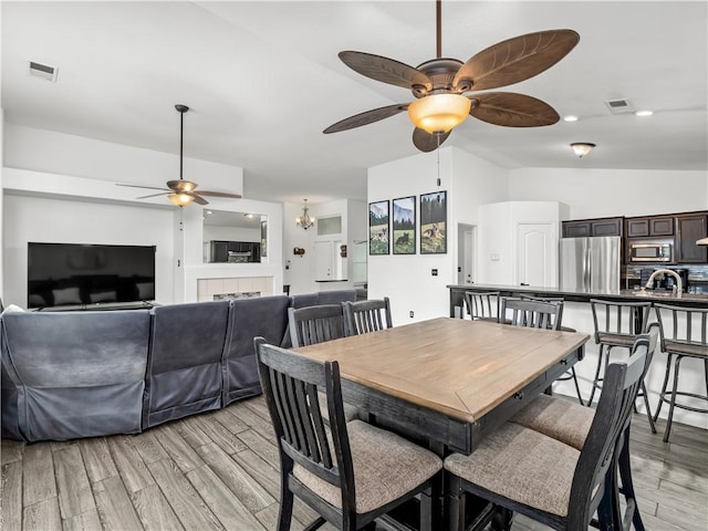 dining area with ceiling fan, light wood-style flooring, lofted ceiling, and visible vents