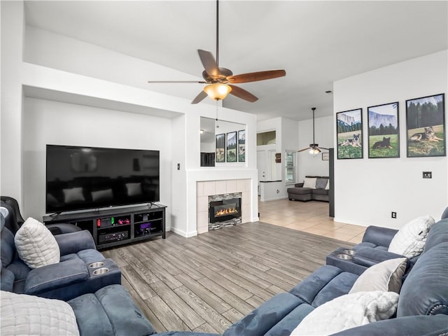 living area featuring ceiling fan, a fireplace, and light wood-style floors