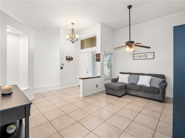 living room with light tile patterned floors, baseboards, and ceiling fan with notable chandelier