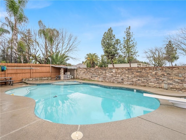 view of pool with a fenced backyard, a diving board, a fenced in pool, and a patio