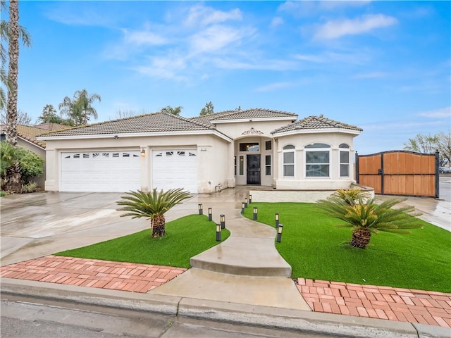 view of front of home featuring stucco siding, a gate, a garage, driveway, and a tiled roof