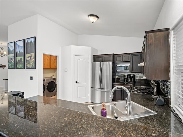 kitchen with lofted ceiling, dark brown cabinetry, a sink, washer and dryer, and appliances with stainless steel finishes