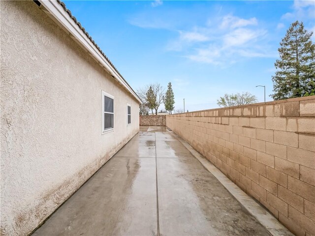 view of side of property featuring a fenced backyard, a patio, and stucco siding