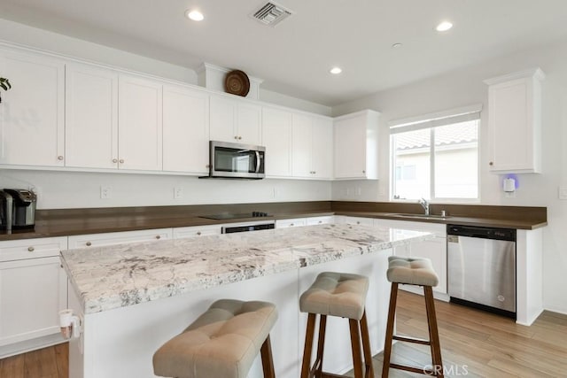 kitchen with appliances with stainless steel finishes, light wood-type flooring, visible vents, and white cabinetry