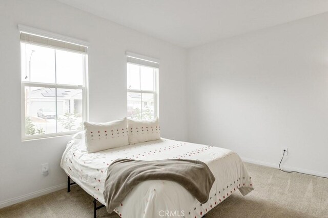 bedroom featuring light carpet and baseboards