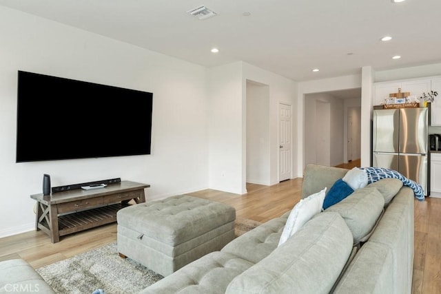 living room featuring baseboards, light wood-type flooring, visible vents, and recessed lighting