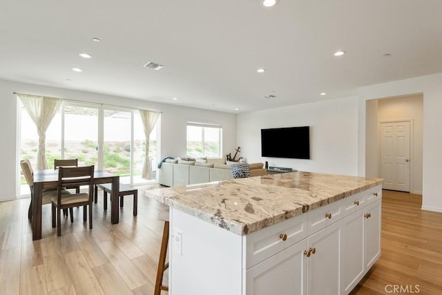 kitchen with recessed lighting, visible vents, white cabinets, a center island, and light wood finished floors