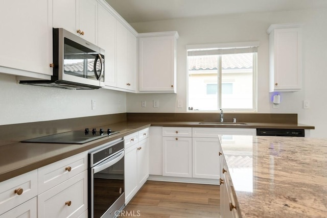 kitchen featuring light wood-type flooring, white cabinetry, appliances with stainless steel finishes, and a sink