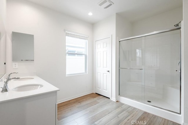 full bathroom featuring a stall shower, visible vents, a sink, and wood finished floors