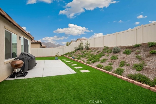 view of yard featuring a patio, a fenced backyard, and a mountain view