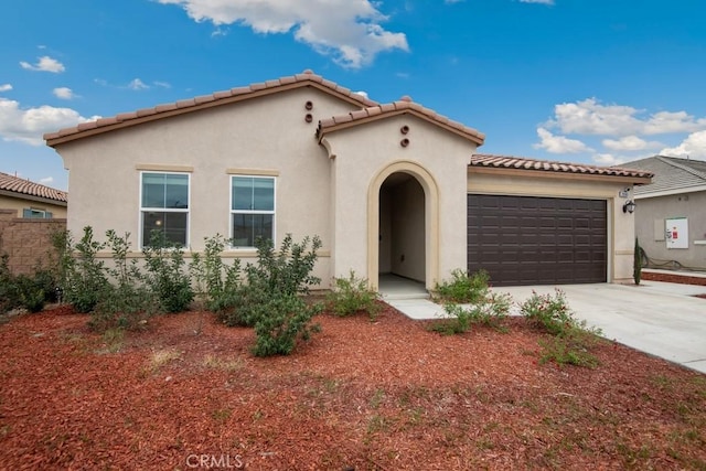 mediterranean / spanish-style house featuring a garage, a tile roof, driveway, and stucco siding