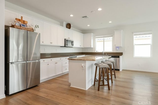 kitchen featuring light wood finished floors, visible vents, appliances with stainless steel finishes, and white cabinets