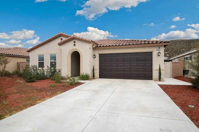 mediterranean / spanish home with driveway, an attached garage, a tile roof, and stucco siding