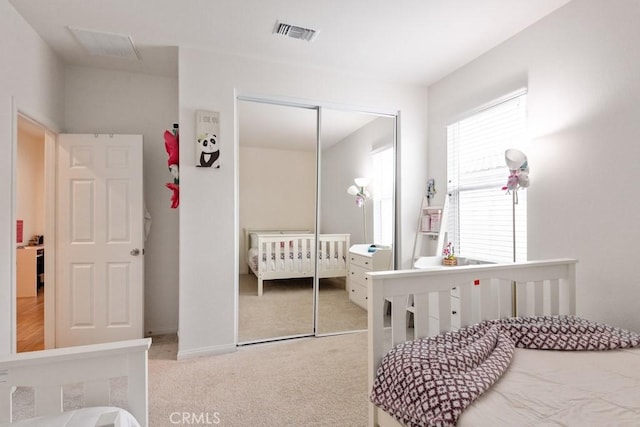 carpeted bedroom with a closet and visible vents