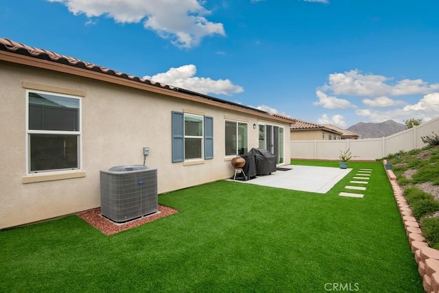 rear view of house featuring a patio, central AC unit, fence, a lawn, and stucco siding