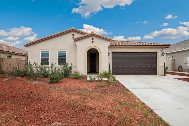 mediterranean / spanish-style home with a garage, a tile roof, concrete driveway, and stucco siding