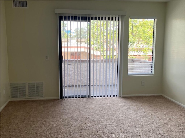 carpeted empty room featuring a wealth of natural light, visible vents, and baseboards