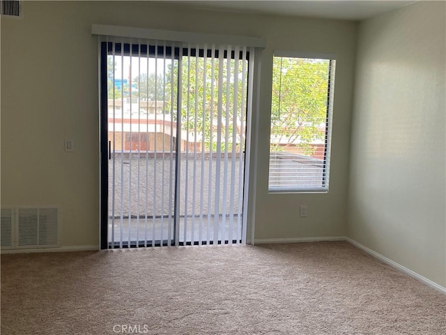 spare room with carpet, visible vents, and baseboards