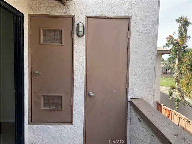 view of exterior entry with visible vents and stucco siding