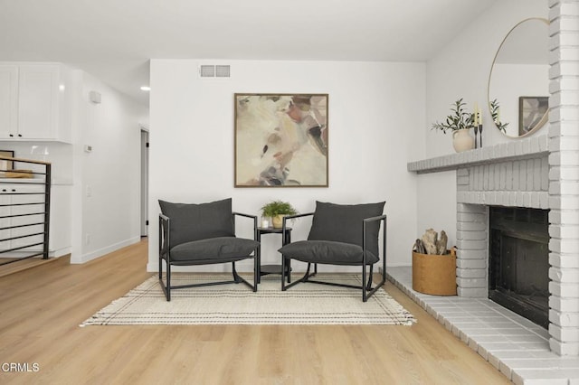 living area featuring light wood-style floors, visible vents, a fireplace, and baseboards