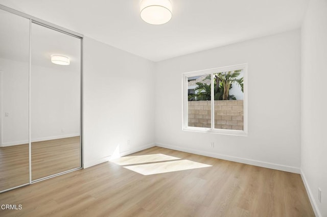 unfurnished bedroom featuring a closet, baseboards, and wood finished floors