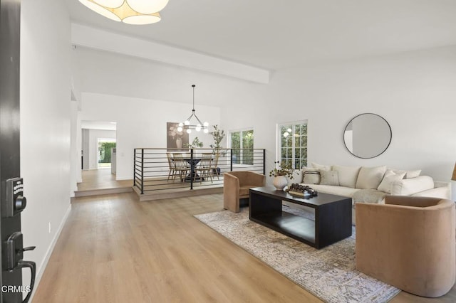 living room featuring baseboards, a chandelier, beamed ceiling, wood finished floors, and high vaulted ceiling