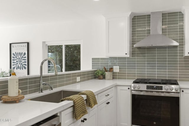 kitchen with tasteful backsplash, wall chimney exhaust hood, white cabinetry, and stainless steel appliances