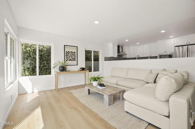 living room featuring light wood-style floors, recessed lighting, plenty of natural light, and baseboards