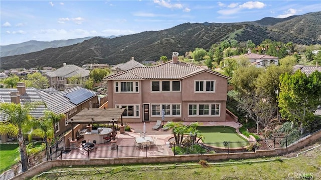 back of property with a fenced backyard, a mountain view, and stucco siding