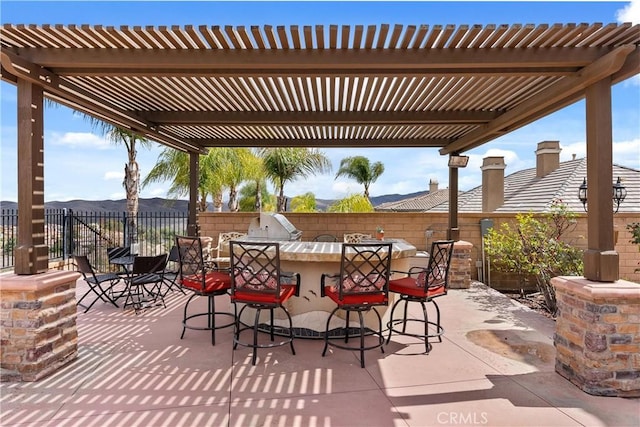 view of patio / terrace with outdoor dry bar, fence, an outdoor kitchen, and a pergola