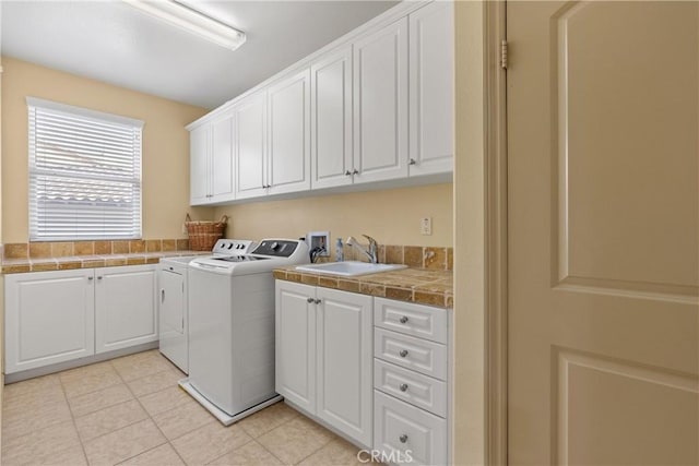 washroom featuring cabinet space, light tile patterned floors, a sink, and washing machine and clothes dryer