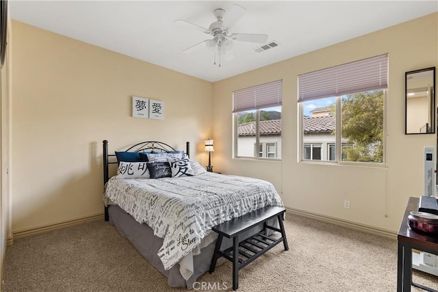 carpeted bedroom with a ceiling fan, visible vents, and baseboards