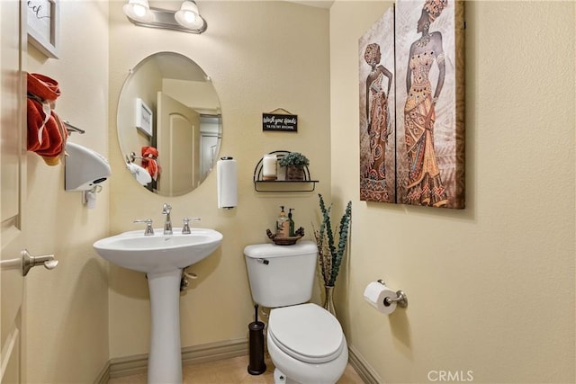 half bathroom featuring a sink, toilet, and baseboards