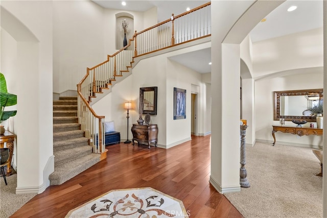 entryway with arched walkways, recessed lighting, a high ceiling, wood finished floors, and baseboards